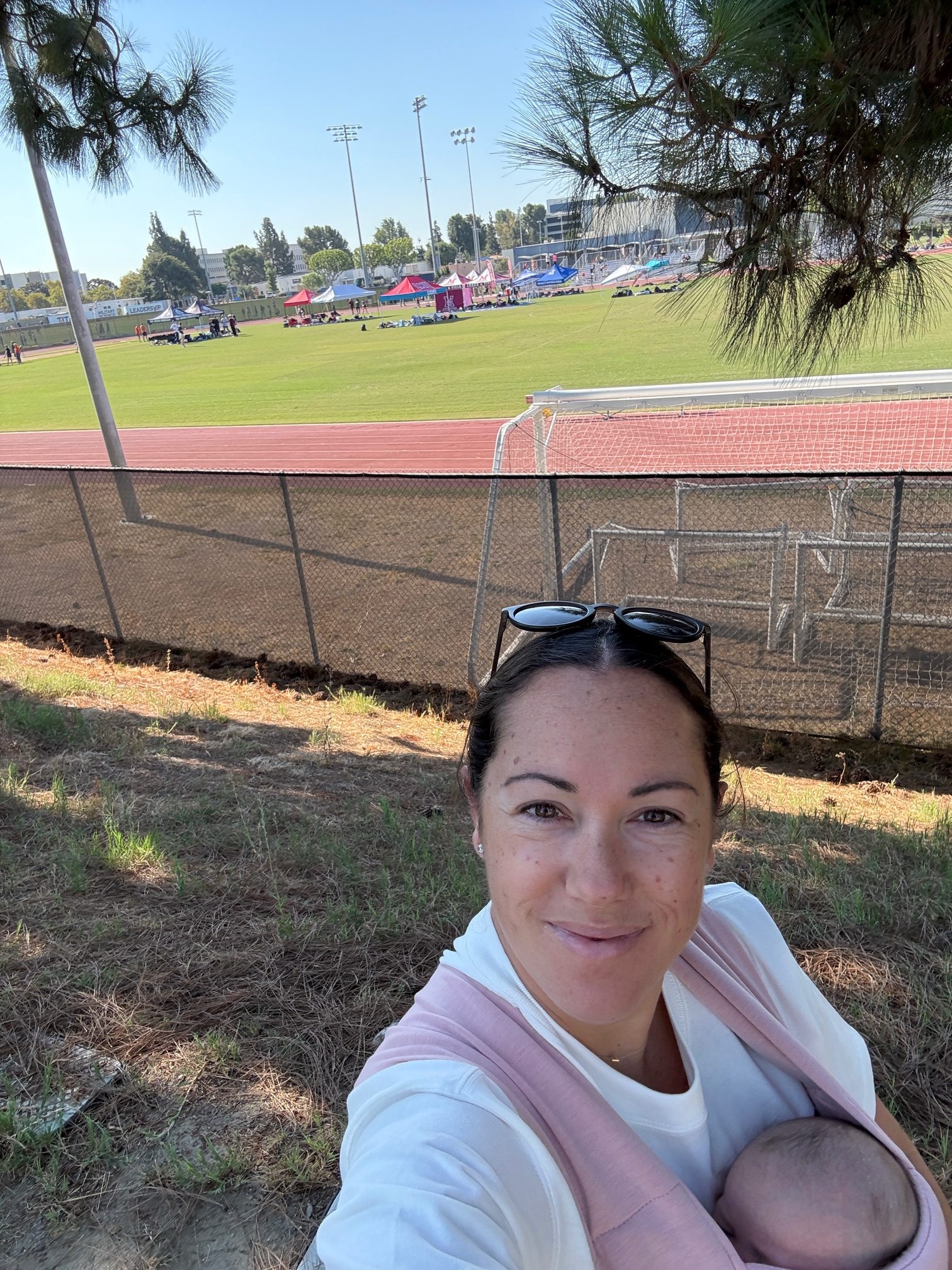 TRR Coach Amanda Hamilton next to a running track with her newborn daughter.